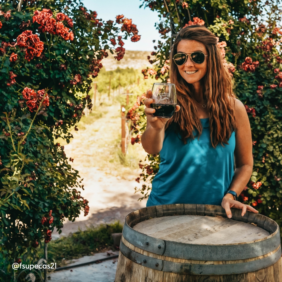 Com'è stato viaggiare nel 2021 - In foto una ragazza con un bicchiere di vino rosso in toscana davanti una botte